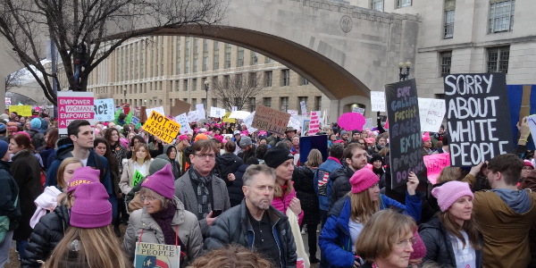 Marchers pass under a stone walkway