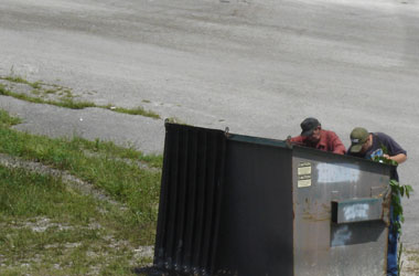 two men go dumpster diving in the middle of the day
