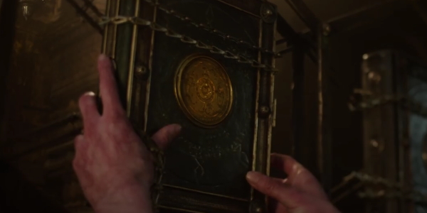 Gnarled hands of Doctor Strange reach for the book of Cagliostro